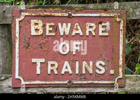 Nahaufnahme von alten alten alten Eisenbahn-Schild isoliert im Freien, Warnung der Öffentlichkeit Beware of Trains, Großbritannien. Stockfoto