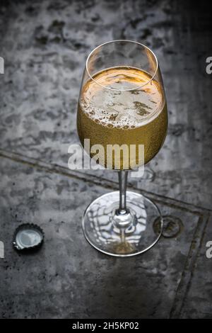 Funkelnder Apfelwein aus Weinglas auf strukturiertem grauen Tongrund Stockfoto
