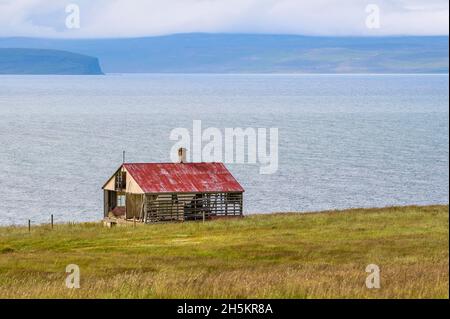 Altes Haus im Sommer an der Küste Nordislands auf der Halbinsel Vatnsnes; Hvammstangi, Nordregion, Island Stockfoto