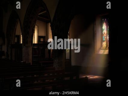 Sonnenlicht strömt durch ein buntes Buntglasfenster auf den Boden einer Kirche; Richmond, North Yorkshire, England Stockfoto