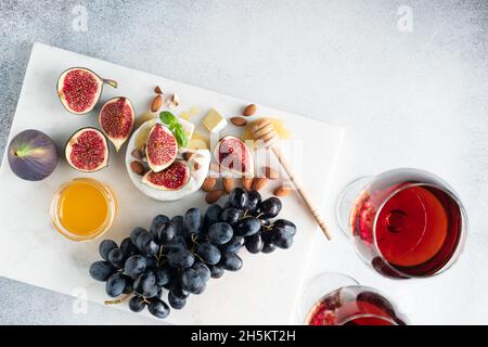 Camembert Käse mit Trauben, Feigen, Nüssen und Wein auf weißem Hintergrund, Draufsicht. Weinsnack-Set Stockfoto