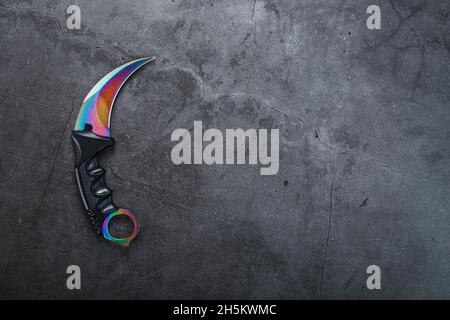 Ein Dolch mit einer Stahlklinge mit einer Farbverlauf-Farbe auf schwarzem Hintergrund. Kantige Waffen, Draufsicht, Freiraum Stockfoto