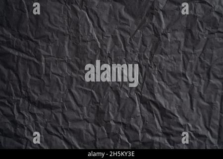 Ein leerer, zerknitterter, dunkelschwarzer, strukturierter Hintergrund aus Seidenpapier Stockfoto