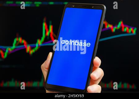 Ukraine, Odessa - Oktober, 9 2021: Coinbase mobile App läuft auf dem Smartphone-Bildschirm mit Trading Candlestick Chart im Hintergrund. Coinbase ist Amerikaner Stockfoto