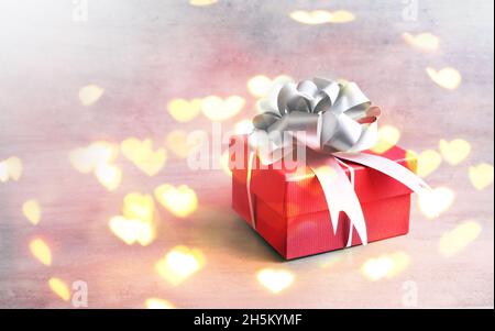 Valentinstagskonzept mit Geschenkbox über herzförmigem Bokeh. Stockfoto