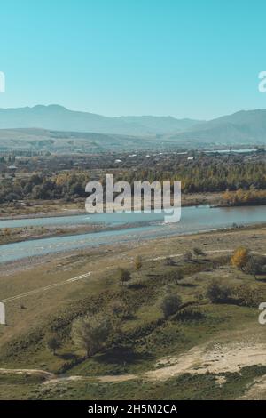 Blick auf den Fluss Mtkvari oder den Fluss Kura von der Felshöhle Uplistsikhe in Georgien, Asien. Flussufer mit Herbstbäumen und Hügeln im Hintergrund Stockfoto