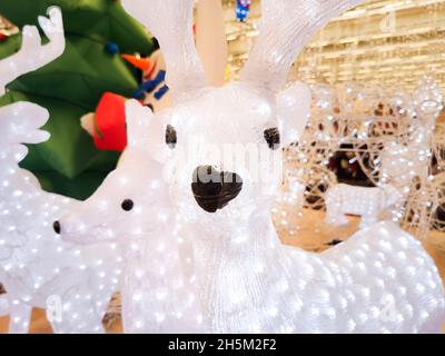 Weihnachtsrentiere, die mit Girlanden geschmückt sind, befinden sich auf der Theke in der Mall Stockfoto