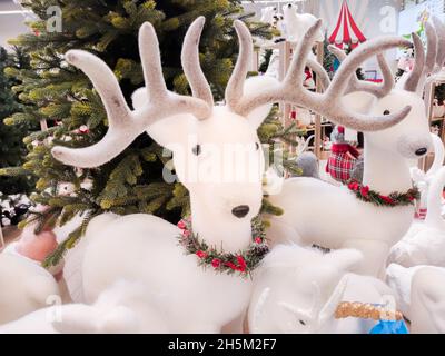 In der Halle des Einkaufszentrums steht ein Plüsch-Hirsch neben einem Weihnachtsbaum zum Verkauf Stockfoto