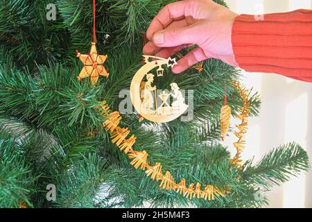 Dekorieren Weihnachtsbaum auf hellem Hintergrund. Hand hält eine weihnachtsbaumdekoration. Konzept für Weihnachten und Neujahr. Stockfoto