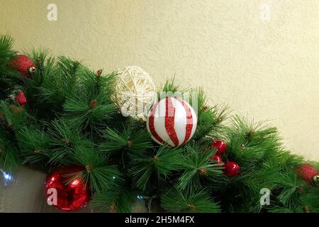Weihnachtsdekoration in Form einer Girlande aus Fichtenzweigen und roten Weihnachtskugeln. Stockfoto