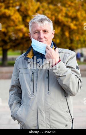 Älterer Mann mit medizinischer Maske im Gesicht, Herbstsaison Stockfoto