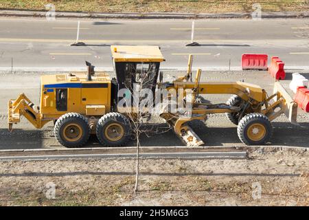 Straßengrader. Moderner Traktor mit zwei Klingen. Vorbereitung des Bodens für Asphalt auf einer Stadtstraße. Straßenbau. Maschinen für schwere Maschinen. Stockfoto