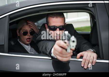Agent im zivilen schwarzen Anzug mit Waffe schützen Prominenten Person im Auto. Sicherheitsschutz für Bodyguard und VIP-Personen. Professioneller Polizeischutz Stockfoto