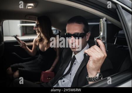 Agent im zivilen schwarzen Anzug mit Waffe schützen Prominenten Person im Auto. Sicherheitsschutz für Bodyguard und VIP-Personen. Professioneller Polizeischutz Stockfoto