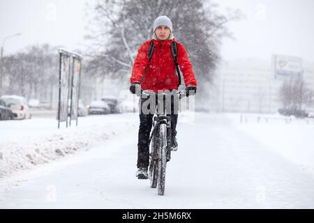 Reiten auf dem Fahrrad in verschneiten und rutschigen Weg in der Wintersaison, kaukasischen Mann mit Fahrrad bewegt sich in der Stadt, Vorderansicht Stockfoto