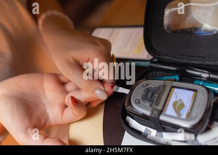 Frau, die auf hohen Blutzucker testet. Frau, die ein Gerät zum Messen des Blutzuckers hält Stockfoto