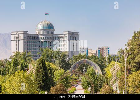 Duschanbe, Tadschikistan. 11. August 2021. Das Steuerkomitee-Gebäude und das Rudaki-Denkmal, vom Rudaki Park aus gesehen. Stockfoto