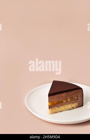 Köstliche Schokolade Mousse Kuchen Scheibe mit den Schichten und Textur auf pastellfarbenen Kaffee farbigen Hintergrund angezeigt. Restaurant-Menü und Süßwarenkonzept. Nahaufnahme. Speicherplatz kopieren. Stockfoto
