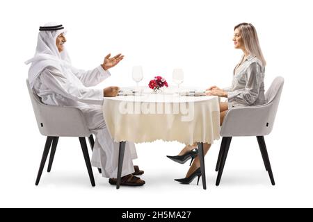 Arabischer Mann und eine junge, schöne Frau sitzen an einem Restauranttisch isoliert auf weißem Hintergrund Stockfoto