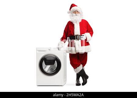 Der Weihnachtsmann lehnt sich auf eine Waschmaschine, isoliert auf weißem Hintergrund Stockfoto