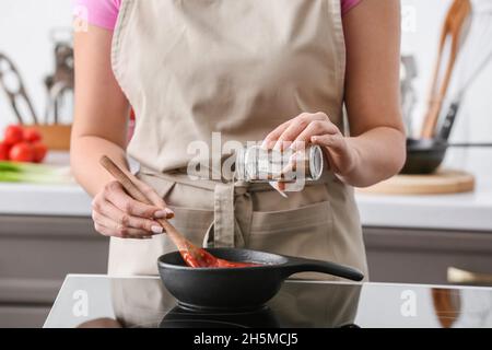 Frau kocht Bio-Tomatensauce in der Pfanne auf Herd in der Küche Stockfoto