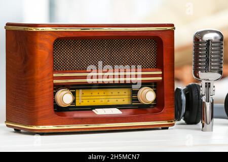 Retro-Radioempfänger mit Mikrofon und Kopfhörern auf dem Tisch im Zimmer Stockfoto