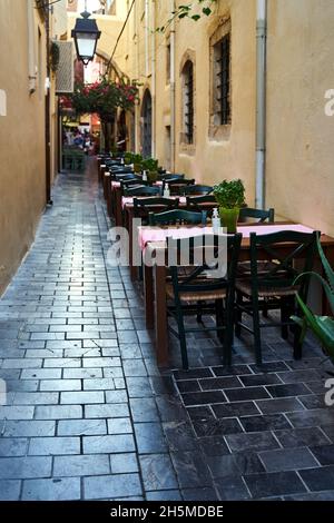 In einer engen Straße der Stadt Chania auf der Insel Kreta in Griechenland stehen Stühle und Tische für Restaurants Stockfoto