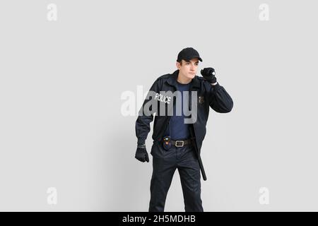 Junger Polizist mit Taschenlampe auf hellem Hintergrund Stockfoto