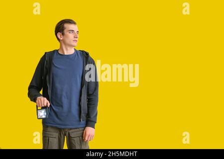 Junger Mann mit Taschenlampe auf gelbem Hintergrund Stockfoto