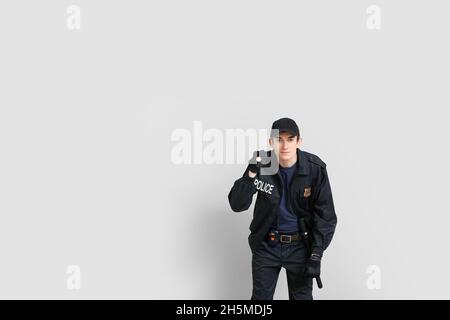 Junger Polizist mit Taschenlampe auf hellem Hintergrund Stockfoto
