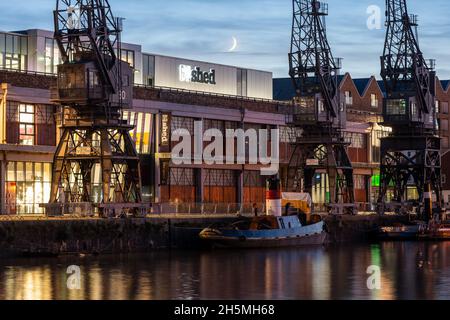 Der Halbmond untergeht über dem M Shed Museum und an den Andockkräne auf der historischen Harbourside von Bristol. Stockfoto