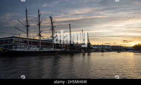 Die Sonne geht über dem M Shed Museum unter und historische Schiffe legen an der Hafenseite von Bristol an. Stockfoto