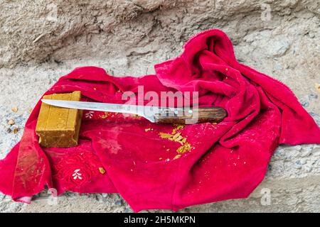 Margib, Provinz Sughd, Tadschikistan. 15. August 2021. Ein Stück Seife und Messer auf einem roten Tuch. Stockfoto