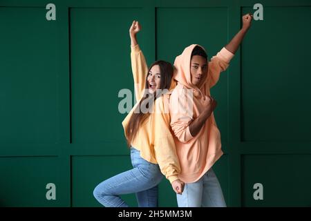 Glückliches junges Paar in Hoodies auf grünem Hintergrund Stockfoto