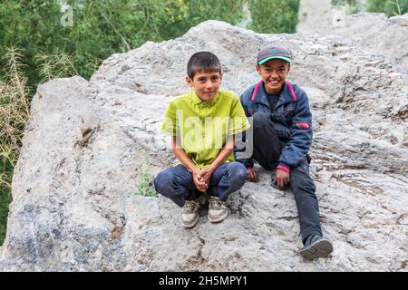 Margib, Provinz Sughd, Tadschikistan. 15. August 2021. Zwei Jungen auf einem Felsen in einem Bergdorf. Stockfoto