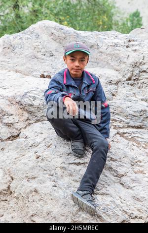 Margib, Provinz Sughd, Tadschikistan. 15. August 2021. Junge auf einem Felsen in einem Bergdorf. Stockfoto