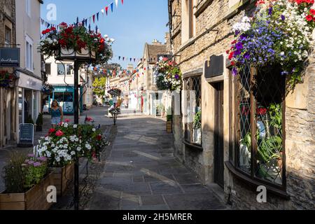 Urige Steinläden sind mit Blumenkästen und Hainenkästen an der traditionellen High Street von Corsham, Wiltshire, dekoriert. Stockfoto