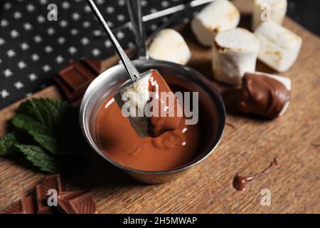 Tauchen Sie leckere gegrillte Marschwalben in Schokolade auf Holzboden Stockfoto