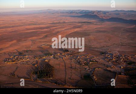 Der Blick von einem Heißluftballon hinunter zum Wüstendorf bei Marrakesch, Sonnenaufgang im April, Marokko Stockfoto