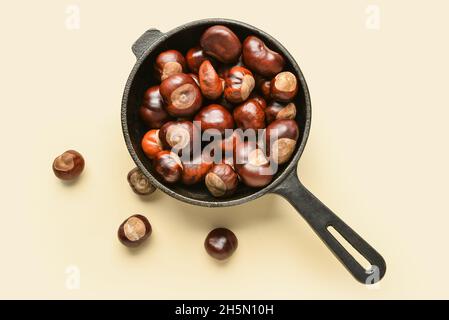 Bratpfanne mit Kastanien auf farbigem Hintergrund Stockfoto