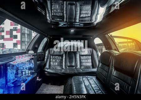 Luxus-Limousine im Innenraum mit schwarzen Ledersitzen und einer kleinen Bar im Innenraum des Autos. Stockfoto