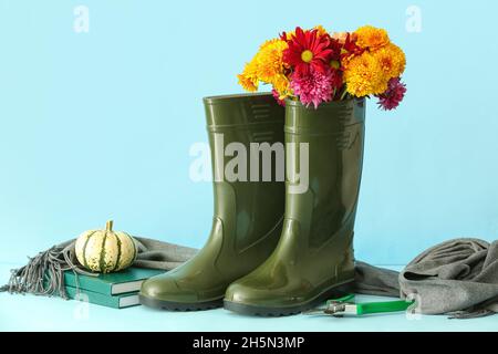 Komposition mit Gummistiefeln, Blumen, Büchern und Scheren auf farbigem Hintergrund Stockfoto