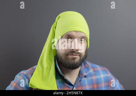 Bärtiger Mann in einem hellgrünen langen Bandana auf dem Kopf und einem karierten blauen Hemd Stockfoto