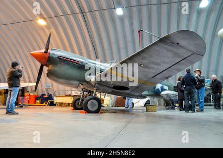 Hangar 11 Curtiss P-40 Warhawk im Hangar in North Weald, Essex, Großbritannien. Tragen einer temporären Lackierung für den Film Red Tails. Verwitterter Effekt Stockfoto