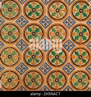 Fragment der Gebäudewand mit glasierten keramischen Fliesen, geprägter Vintage Mudejar, Nahaufnahme. Traditionelle, reich verzierte spanische Architektur. Abstrakter Hintergrund. Stockfoto