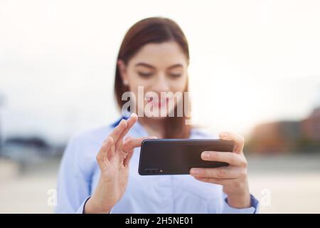 Junge rothaarige kaukasische Geschäftsfrau, die online surfen Smartphone im Freien Stockfoto