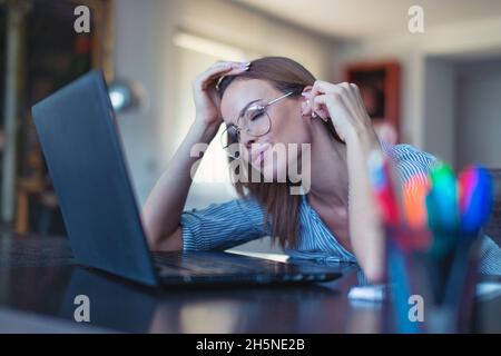 Junge kaukasische Frau mit Freisprecheinrichtung, die Musik am Laptop hört, Augen geschlossen Stockfoto