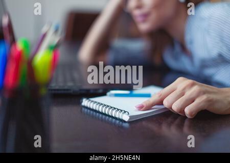 Die junge Geschäftsfrau zeigt mit der Hand auf das Notebook im Schreibtisch des Heimbüros Stockfoto