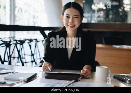 Geschäftsfrau tun Finanzbuchhaltung Börsengraphen Analyse auf Papierkram im Büro Stockfoto