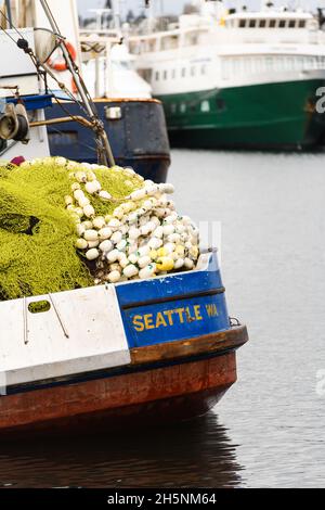 Seattle - 09. November 2021; Ein Fischerboot mit Seattle WA in Gold auf blauem Heck. Fischernetze und Schwimmer werden hoch auf dem Schiff angehäuft Stockfoto